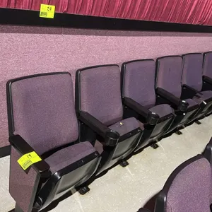 Row of 6 floor-mounted movie theater seats. Features purple fabric upholstery, cushioned foldable seats, and armrests with integrated cup holders. Not