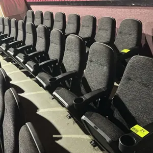 Unbranded 6-seat floor-mounted movie theater seating row. Features textured dark gray cloth upholstered cushioned high-back seats and flip-up bottoms.