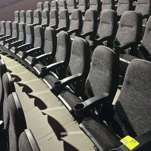 Row of (4) floor-mounted movie theater seats. Features dark gray textured cloth cushioned upholstery with flip-up seats. Equipped with black plastic a