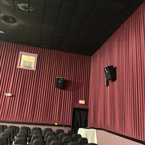 Movie theater wall-mounted acoustic sound curtains. Features a vertically pleated, burgundy-colored textured fabric design for sound attenuation. Moun