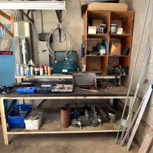 WORK BENCH WITH ASSORTED SHOP ITEMS- HEAVY DUTY CASTERS, BENCH VICE, HOLE SAWS, TOOL BOX,