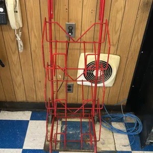 Metal 3-tier hand dolly. Features a red painted tubular metal frame with three angled wire rack tiers designed for convenient product transport. Equip