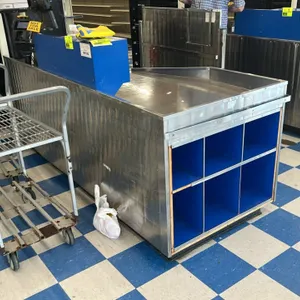AFCO stainless steel checkout lane. Features integrated blue shelving cubbies, a cash drawer, and register stand area. 9'L. Note: Register, scanner, P