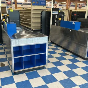 AFCO stainless steel checkout lanes. Features stainless steel wrap construction, blue end-cap shelving with six compartments, integrated bag well, and