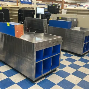AFCO stainless steel checkout lanes. Features stainless steel construction, integrated bagging area with six blue cubbies, and side shelving/organizer
