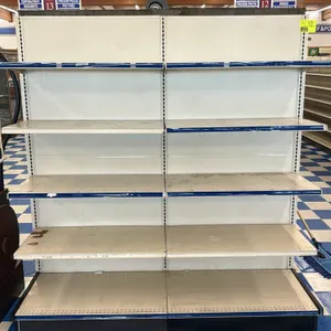 12'L of Lozier wall shelving. Features cream-colored metal uprights, solid back panels, adjustable upper shelves, and blue price tag channels. Include