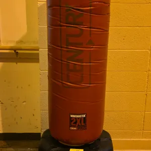 Century Wavemaster 2XL Pro freestanding training bag. Features a high-density foam-filled striking surface with a red vinyl cover. Mounted on a low-pr