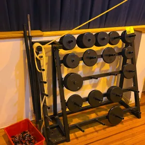 Metal weight stand with weights, bars, and clamps. Features a black-finished steel frame with multiple plate storage horns and vertical bar storage. I