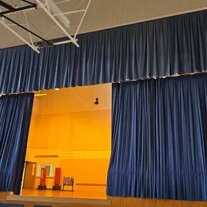 Blue stage curtains. Features a pleated fabric design with bottom ballast weights. Dimensions: Approximately 16' to 50'H. Stage accessories, cart, she
