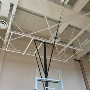 Ceiling-mounted basketball hoop system. Features a glass backboard, orange breakaway rim, motorized ceiling-hung support structure, and a Saf-Lok safe