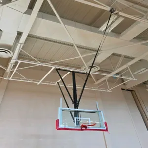 Ceiling-suspended basketball hoop. Features a transparent glass backboard with red protective padding, orange breakaway rim, and a motorized folding f