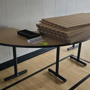 Laminate wood table. Features a curved light wood-grain laminate top with black trim. Mounted on a black metal base. Dimensions: 99" x 30"H. Note: Sla