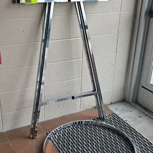 Chrome metal clothes merchandiser. Features an A-frame upright stand and a separate circular rack ring. Designed for retail garment display. Note: Dis