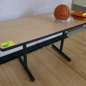 Laminate wood table. Features a light wood-look laminate top with black edge banding. Mounted on a black metal T-base. 60"L. Contents not included.