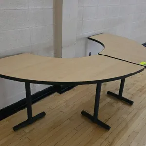 Two-piece modular laminate wood crescent table. Features a light wood grain laminate top and black metal T-base legs. Dimensions: 99" x 30"H.