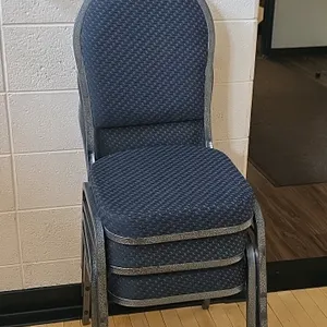 Upholstered cushioned metal base banquet chairs. Features blue patterned fabric upholstered seats and crown-style backrests. Hammered silver-tone meta