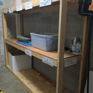 Closet contents lot. Includes a wood shelving unit measuring 96" x 73"H, a 72" poly folding table, and a metal folding chair. Also includes a broom, p
