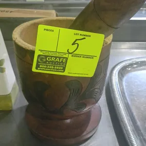Wooden mortar and pestle set. Features hand-carved floral designs on the exterior of the mortar. Includes matching wooden pestle. Note: Mortar rim sho