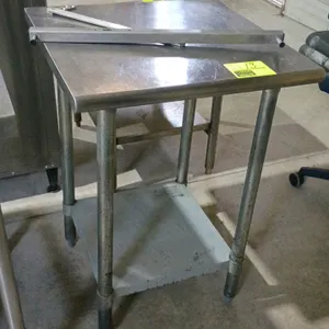 Stainless steel table. Features a stainless steel top, undershelf, and adjustable bullet feet. Includes loose metal bracket hardware shown on top. Dim