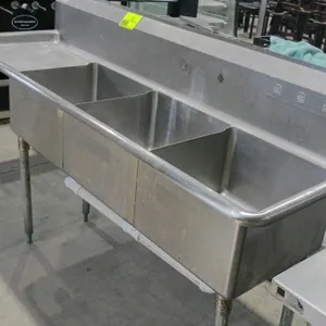 Stainless steel 3-bay compartment sink. Features a left-side drainboard, high backsplash with pre-drilled faucet mounting holes, and an under-sink PVC