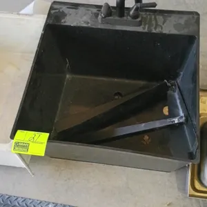 Utility sink. Features a black plastic single basin equipped with a deck-mounted dual-handle faucet. Includes two black metal support legs inside the 