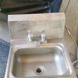 Stainless steel wall-mount hand sink. Features a backsplash, integrated splash-mount faucet with dual knobs, drain, P-trap, and flexible supply lines.