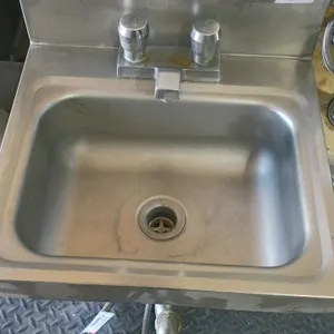 Stainless steel wall-mount hand sink. Features integrated backsplash, dual-knob faucet, and drain assembly with flexible water lines. Dimensions: 16"x