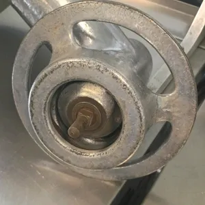 Commercial meat grinder attachment. Features a cast metal body, removable feed pan, and white plastic stomper. Designed for standard power hub compati