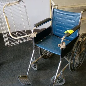 Invacare Tracer wheelchair. Features a blue vinyl padded seat and backrest, chrome-plated metal frame, dual footrests, and padded armrests. Equipped w