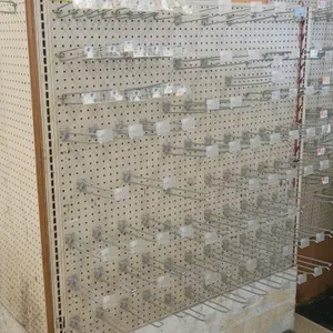 Pegboard display fixture. Features double-sided pegboard panels and includes numerous metal merchandise peg hooks. Mounted on a wood-style base frame.