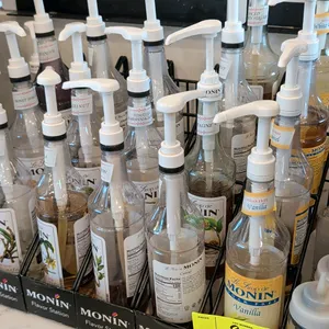 Monin Flavor Station wire syrup bottle display racks. Includes assorted Monin flavoring syrup bottles and dispensing pumps. Features multi-tier wire c