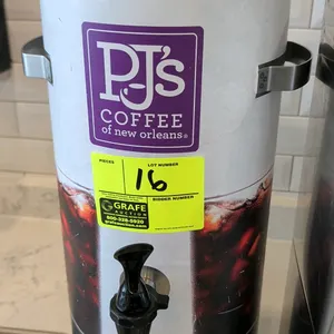 Stainless steel cold brew drink dispenser. Features front dispensing spigot, side carrying handles, top lid, and PJ's Coffee graphic wrap.