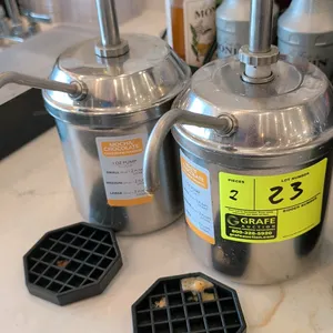Stainless steel sauce and condiment pump dispensers. Features stainless steel canisters with manual plunger pump assemblies and curved dispensing spou
