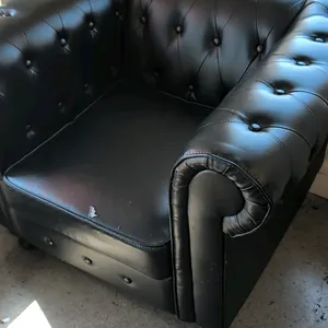 Pair of tufted club armchairs. Features black vinyl upholstery, button-tufted back and rolled arms, and removable seat cushions. Note: Both seat cushi