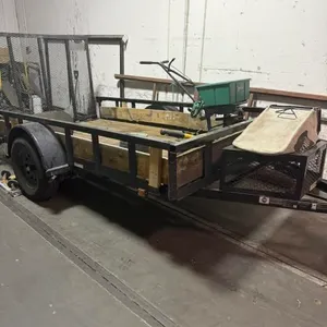 Single-axle utility trailer. Features a steel frame, wood deck, mesh side rails, and a mesh cargo basket on the tongue. Note: Walk-behind broadcast sp