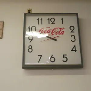 A Vintage "Drink Coca-Cola" Wall Clock. (Coca-Cola) A square commercial advertising wall clock featuring a white face with the classic red "Drink Coca