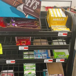 Assorted retail gum and candy contents. Includes Hershey's chocolate bars, Kit Kat, Halls drops, and assorted chewing gum packages including Trident, 