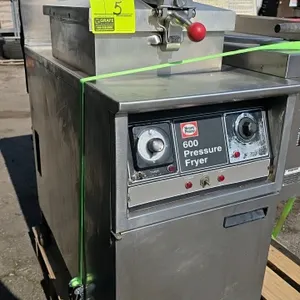 1997 Henny Penny 600 natural gas commercial pressure fryer. Features dial timer, analog temperature control, locking lid assembly, fry basket, and fil