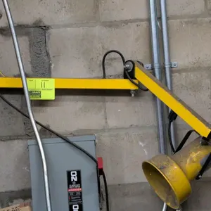 Metal adjustable shop light. Features articulated dual-arm extension, yellow metal construction, adjustable lamp fixture, and wall-mounting bracket.