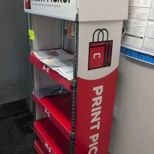 Metal 5-tier print pickup display rack. Features chrome wire uprights, red shelving tiers with alphabetical section labeling (A-E, F-L, M-S, T-Z), and