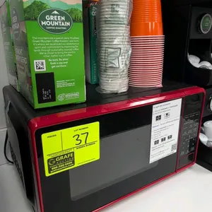 Countertop microwave oven. Features digital keypad controls, push-button door release, and red accent trim. 17"W. Contents on top and surrounding equi
