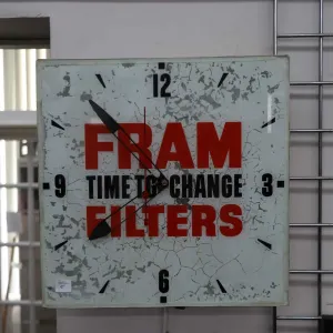 Vintage "Fram Filters" metal electric wall clock with glass face, partially lights up, working at ti