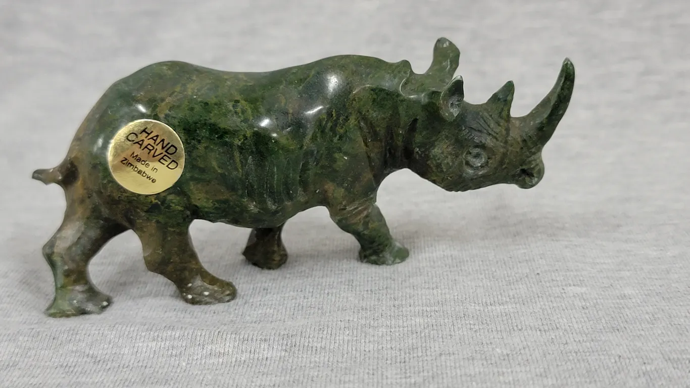 A Rhinoceros hand carved out of Verdite from the Shona Villages in Zimbabwe. Approximately 1.75" tall x 4" long. A