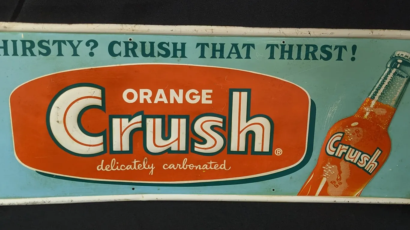 EMBOSSED TIN SIGN THIRSTY? CRUSH THAT THIRST! ORANGE CRUSH DELICATELY CARBONATED