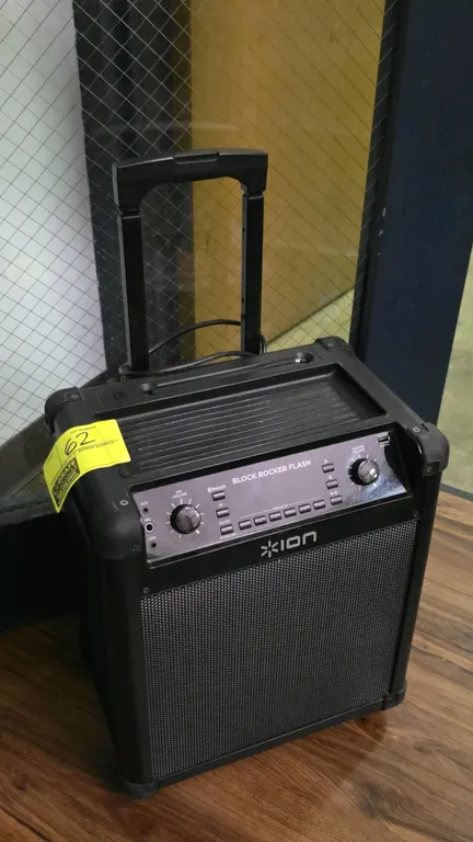 ION Block Rocker Flash portable speaker. Features Bluetooth connectivity, AM/FM radio, retractable telescoping handle, and rolling wheels. Front panel