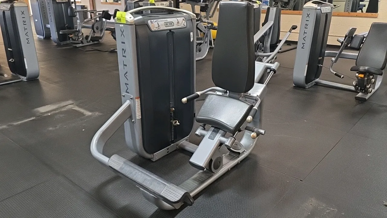 Matrix G7-S77 calf extension exercise machine. Features an adjustable padded seat and backrest, an integrated weight stack with selector pin, and a to
