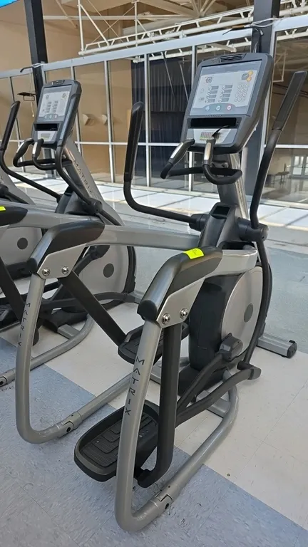 Matrix E-3x elliptical trainer. Features an integrated console with a cooling fan, numeric keypad, and multiple workout programs. Equipped with contac