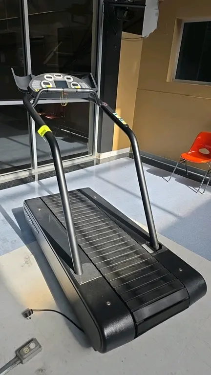Woodway MERC-S treadmill. Features a slat-belt running surface, digital LCD console with time, distance, heart rate, speed, and incline displays, hand