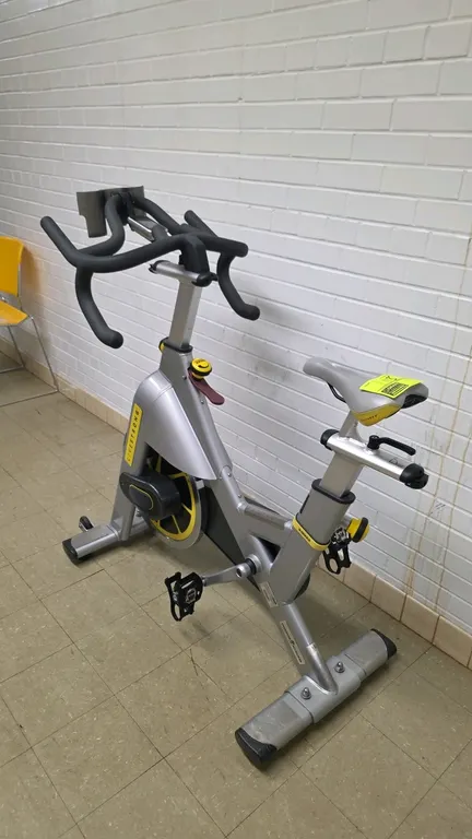 LiveStrong LS S-Series Class S indoor cycling bike. Features a silver-tone frame with yellow accents, adjustable seat and handlebars, digital console,