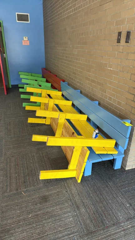 Painted wood benches. Features solid wood construction with integrated backrests. Painted in various bright colors including blue, yellow, green, and
